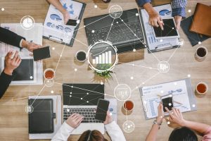 Des personnes sur un bureau avec des smartphones, des tablettes et des ordinateurs, avec des liens digitaux